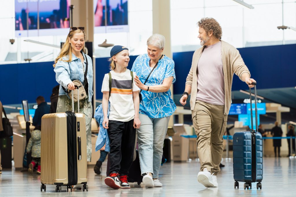 Perhe matkalaukkujen kanssa lähtöterminaalissa.